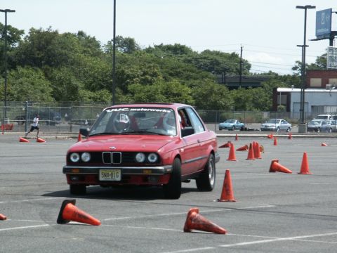 2001 Mercury Grand Marquis - A red BMW E30 coupe navigates an autocross course marked by orange traffic cones.