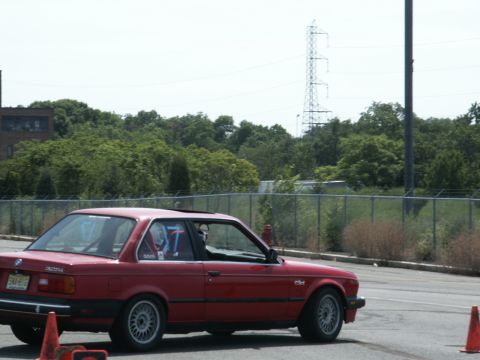 2001 Mercury Grand Marquis - A red BMW sedan is seen on a race track with orange cones marking the course.