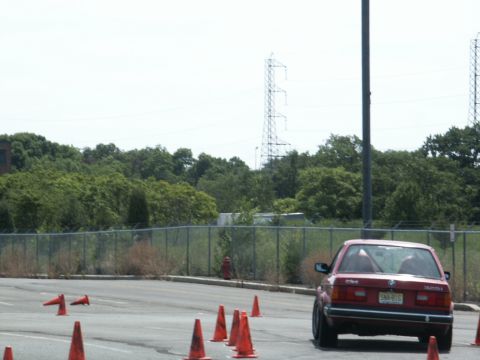 2001 Mercury Grand Marquis - A red sedan with a visible roll cage navigates an autocross course marked by orange cones.