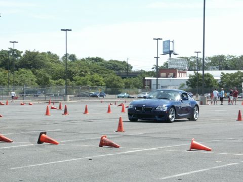 2001 Mercury Grand Marquis - A blue BMW Z4 coupe is seen on a race track during an autocross event, with numerous orange cones marking the course.