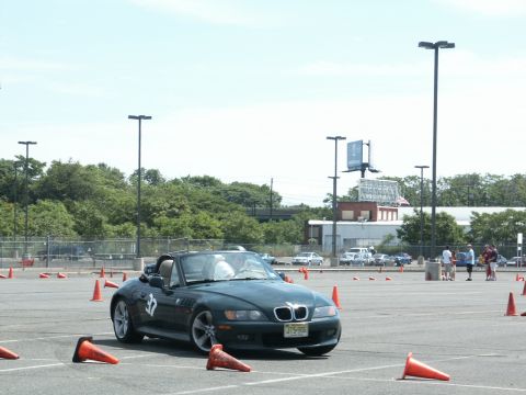 2001 Mercury Grand Marquis - A dark green BMW Z3 convertible navigates an autocross course marked by orange cones.