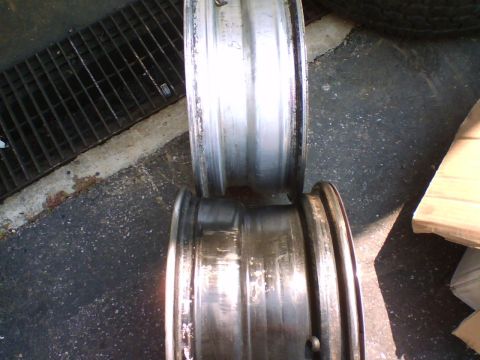 1979 Ford Bronco - Two aluminum wheels are shown, one on top of the other, with visible dirt and wear.