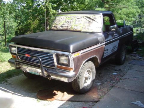 1979 Ford Bronco - This Ford truck, possibly a 1979 model, features a prominent front bull bar and camouflage tape obscuring the windshield.
