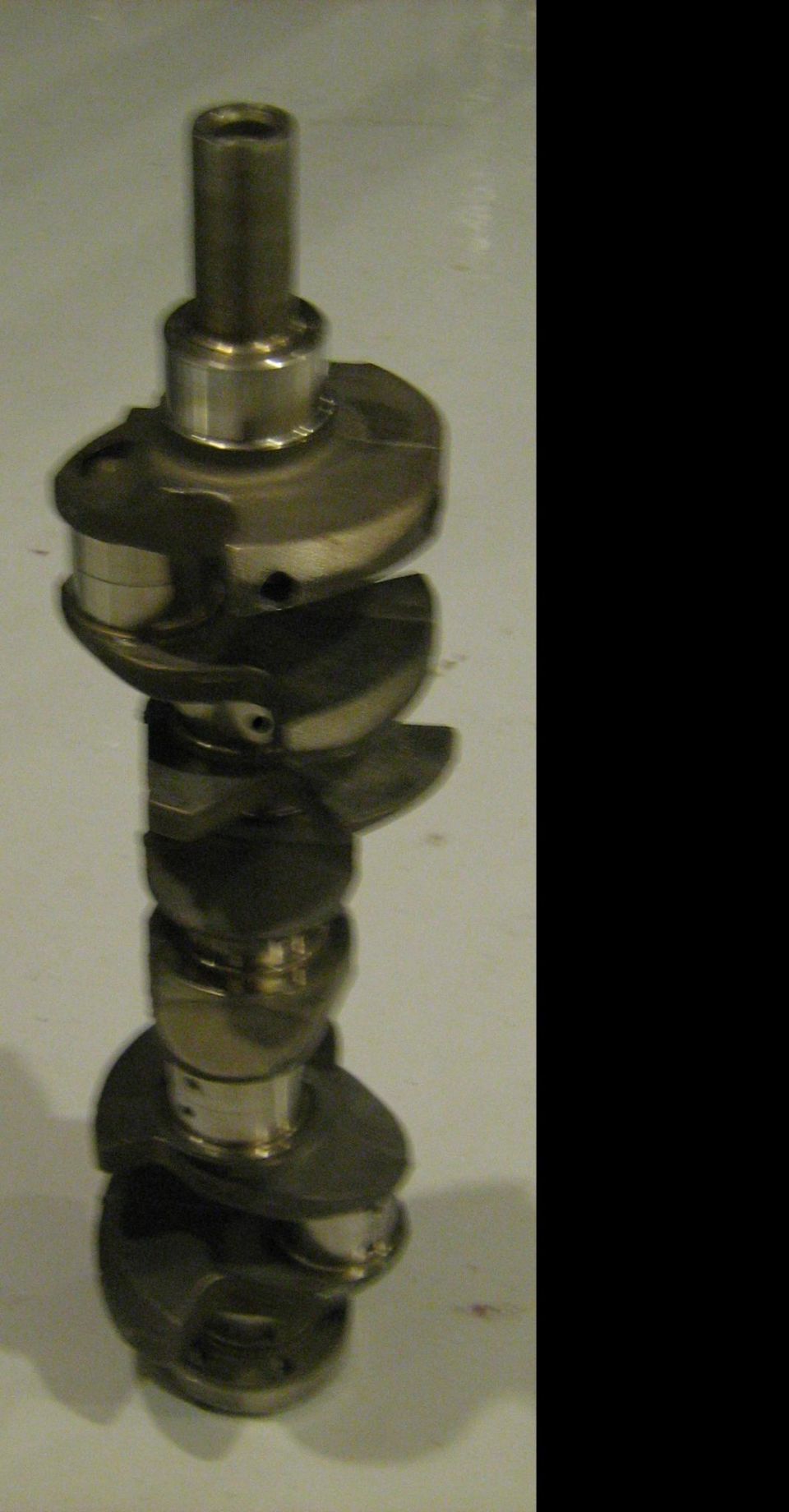 Engine crankshaft standing vertically against a wall