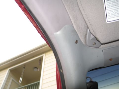1995 Ford Bronco - Close-up of the interior A-pillar trim and sun visor, with a warning label attached.