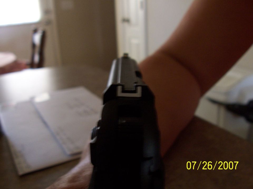 Rear sight view down the slide of a black handgun held indoors, dated 07/26/2007