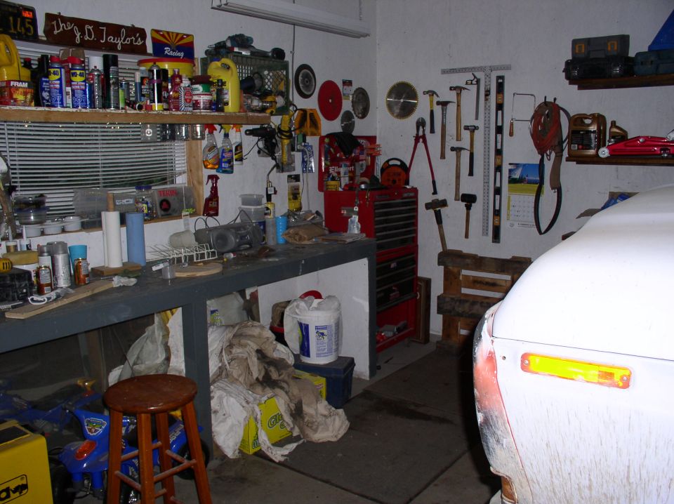 White vehicle front fender with amber marker light parked in a cluttered garage workshop