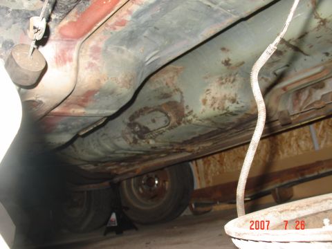1973 Ford Ranchero - The underside of a vehicle is shown, with visible rust on the floorboards and suspension components.