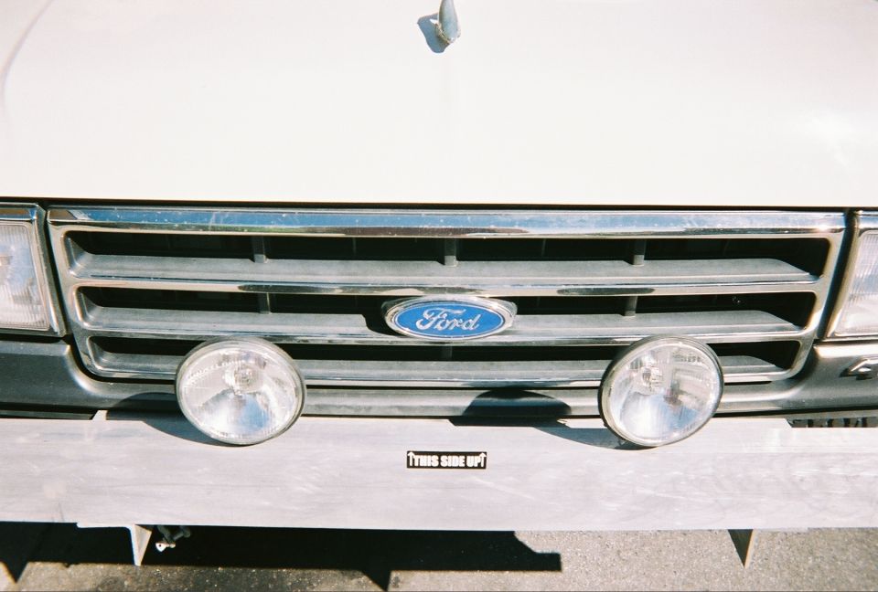 1991 Ford Bronco front grille with Ford logo, two fog lights, and a 'THIS SIDE UP' sticker