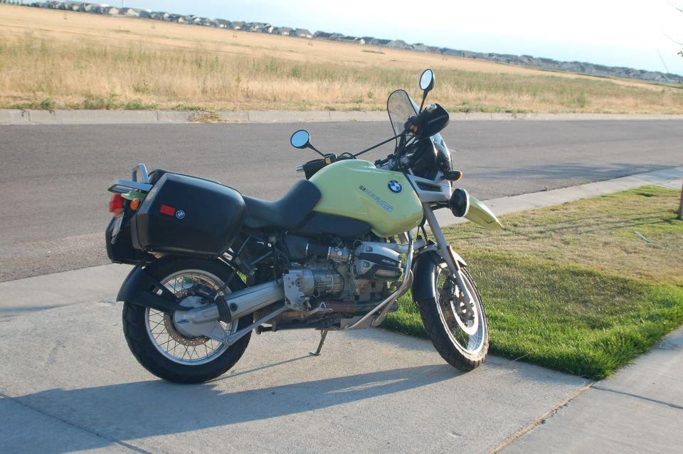 Lime-green BMW boxer motorcycle with hard saddlebags parked on a suburban sidewalk