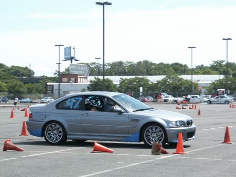 2001 Mercury Grand Marquis - A silver BMW M3 coupe, identified by the number 47, maneuvers through an autocross course marked by orange cones.