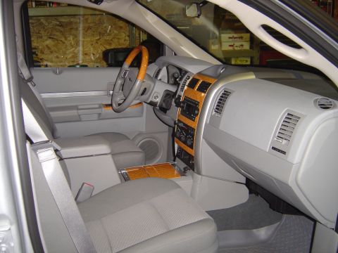1978 Ford Bronco - The interior of a gray SUV features wood trim accents on the dashboard and center console, along with a tan steering wheel.