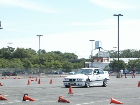 2001 Mercury Grand Marquis - A white BMW E36 coupe navigates a course marked by orange traffic cones on a sunny day.