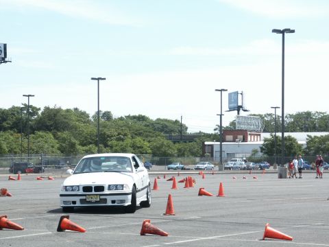 2001 Mercury Grand Marquis - A white BMW E36 sedan is seen on an autocross course with orange cones marking the path.