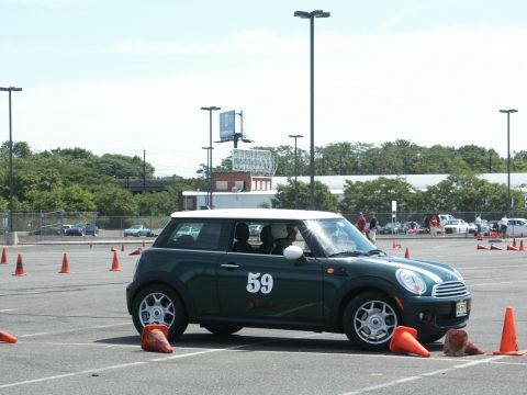 2001 Mercury Grand Marquis - A green Mini Cooper is parked on an asphalt lot, surrounded by orange cones, with other vehicles visible in the background.