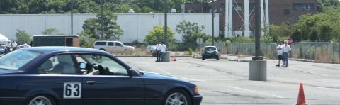 2001 Mercury Grand Marquis - A blue coupe with racing number 63 is seen on a paved lot with other vehicles and people.