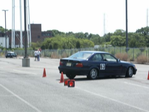 2001 Mercury Grand Marquis - A dark blue coupe with racing number 63 navigates a course marked by orange cones on a paved lot.