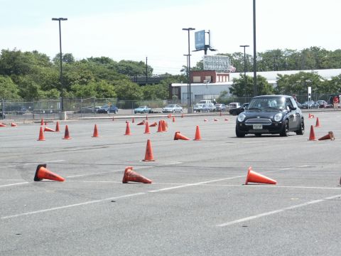 2001 Mercury Grand Marquis - A black Mini Cooper navigates an autocross course marked by orange cones in a parking lot.
