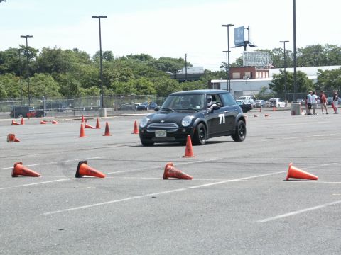 2001 Mercury Grand Marquis - A black Mini Cooper navigates a course marked by orange traffic cones on a sunny day.