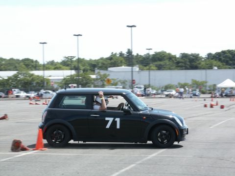2001 Mercury Grand Marquis - A black Mini Cooper navigates a cone course, with a driver waving from the window.