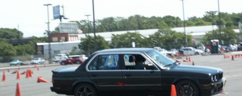 2001 Mercury Grand Marquis - A dark sedan navigates an autocross course marked by orange cones, with other vehicles visible in the background.