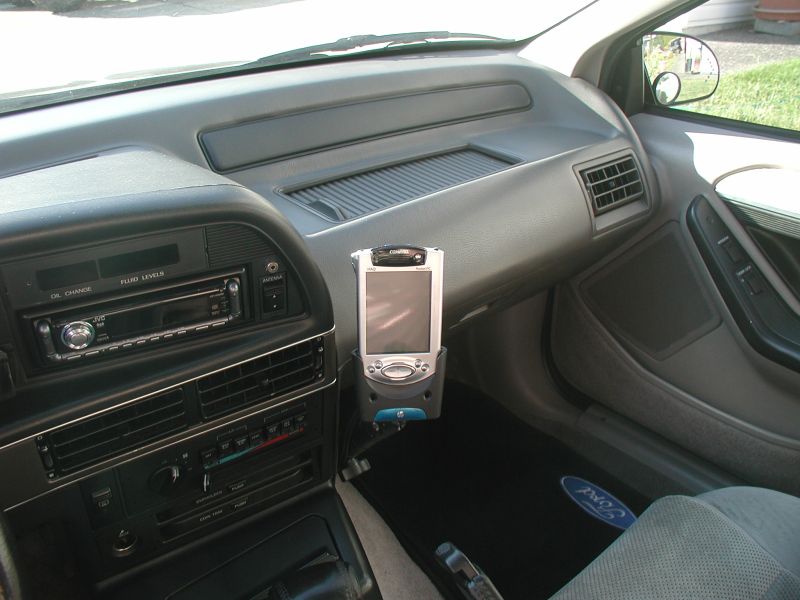 Car dashboard with aftermarket stereo and PDA mounted in center console cradle