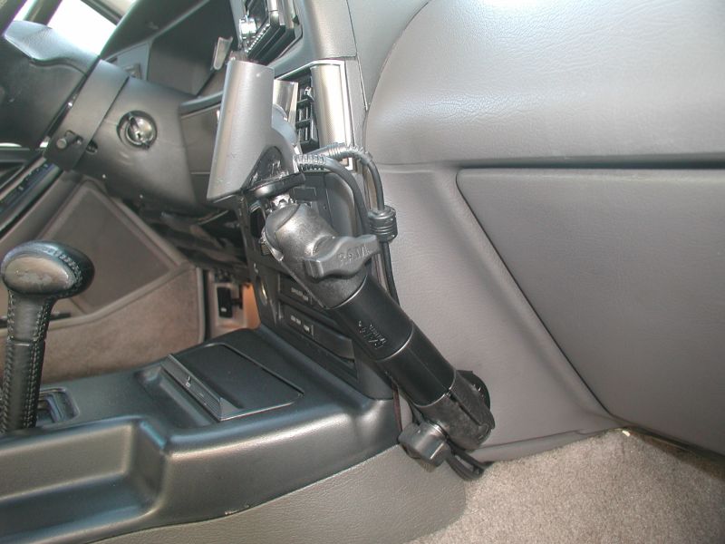 Black articulating device mount bolted to gray car center console with cable routed to dash