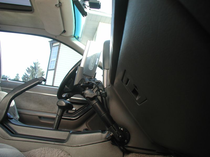 PDA on articulating console mount beside steering wheel in gray car interior