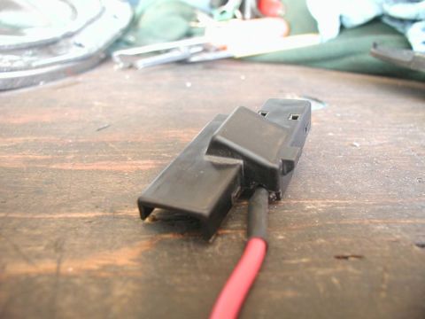 1990 Ford Thunderbird - Close-up of a black plastic electrical connector and a red wire on a wooden table.