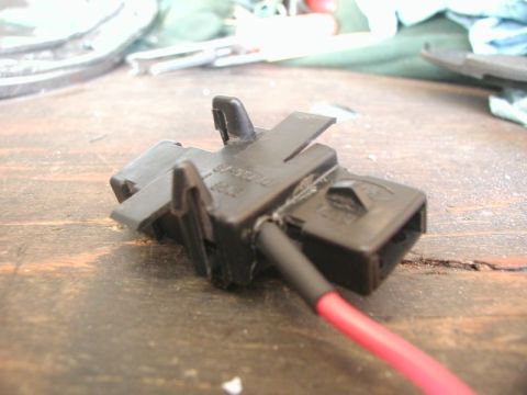 1990 Ford Thunderbird - Close-up of a black trunk light connector with a red wire attached. Part number is visible on the housing.
