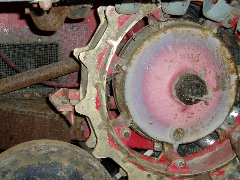Snow trac mechanism with a toothed wheel and a central hub, showing rust and wear