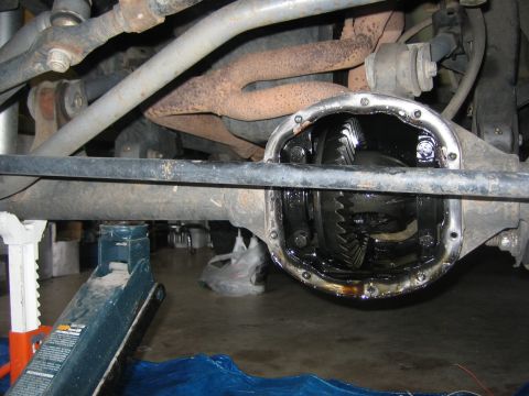 2001 Jeep Wrangler - Solid axle housing with the differential cover off and gear oil drained, showing the oil-blackened ring gear and carrier through the open h…