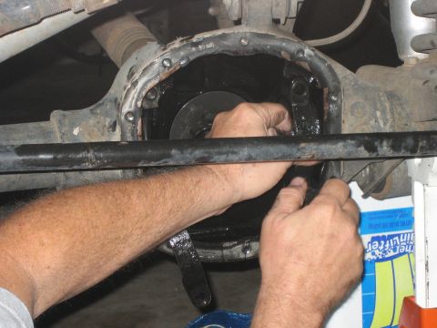 2001 Jeep Wrangler - Hands work on an open differential cover, likely during a repair or modification.