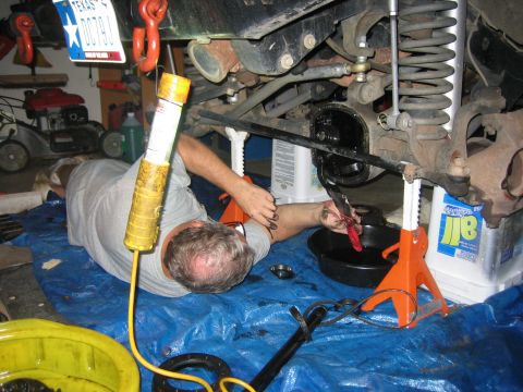 2001 Jeep Wrangler - Mechanic performs maintenance on a vehicle's differential in a garage setting.