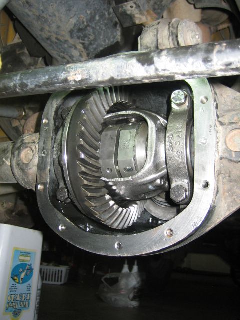 2001 Jeep Wrangler - Underside view into an axle housing with the differential cover removed, exposing the ring and pinion gear, carrier and bearing caps still…