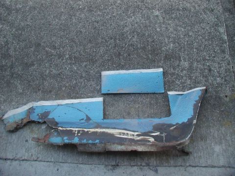 1990 Ford Thunderbird - Damaged blue automotive trim pieces are shown resting on a concrete surface.