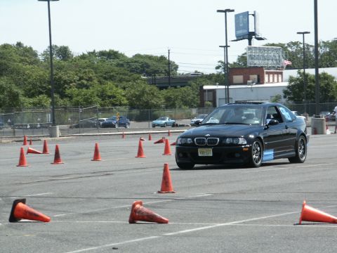 2001 Mercury Grand Marquis - A black BMW coupe drives through an autocross course marked by orange cones on a sunny day.