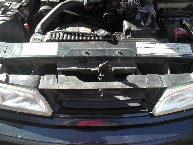 Car's engine bay with radiator, hoses, and battery visible
