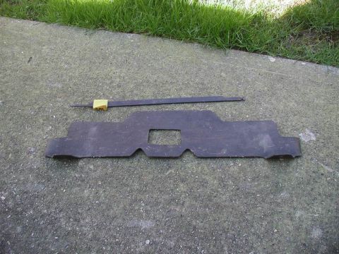 1990 Ford Thunderbird - A dark, irregularly shaped air guide part is shown on a concrete surface next to a metal rod with a brass fitting.