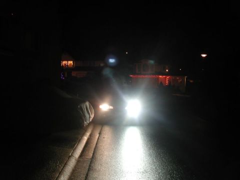 1990 Ford Thunderbird - Headlights illuminate a street at night, with holiday decorations visible on houses.