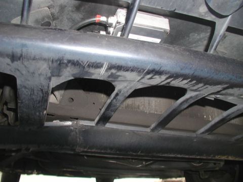 1990 Ford Thunderbird - A close-up shot reveals an electronic module and wiring affixed to the underside of a vehicle's plastic shielding.