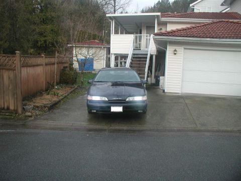1990 Ford Thunderbird - A 1990 Ford Thunderbird is parked in a driveway in front of a house and garage.