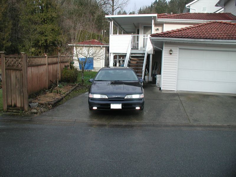 1990 Ford Thunderbird parked in driveway in front of a house and garage