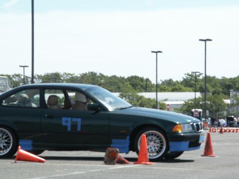 2001 Mercury Grand Marquis - A dark green coupe, possibly a BMW E36, navigates an autocross course with orange cones.
