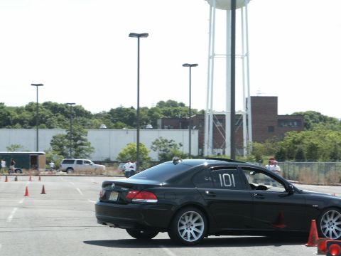 2001 Mercury Grand Marquis - A black sedan with racing numbers participates in an event, with a water tower in the background.
