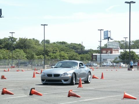 2001 Mercury Grand Marquis - A silver BMW Z4 coupe is seen on an autocross course, maneuvering around orange traffic cones under a clear sky.