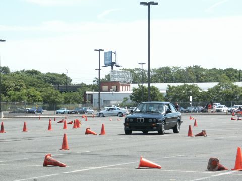 2001 Mercury Grand Marquis - A black BMW E30 coupe navigates an autocross course marked by orange cones.