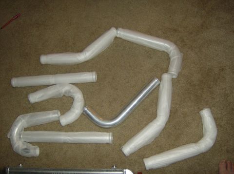 1996 Ford Probe - Various automotive hoses and pipes are arranged on a carpeted floor, some still in protective wrapping.