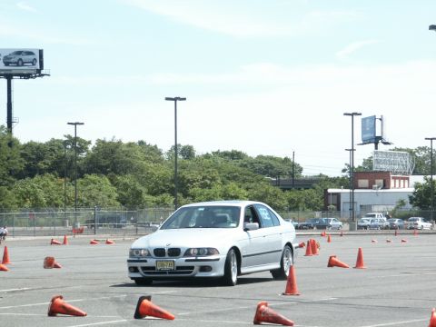 2001 Mercury Grand Marquis - A silver BMW sedan drives through an autocross course on a sunny day, with other vehicles visible in the background.