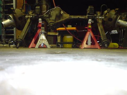 1977 Ford Bronco - A vehicle's rear axle assembly is supported by jack stands in a workshop.